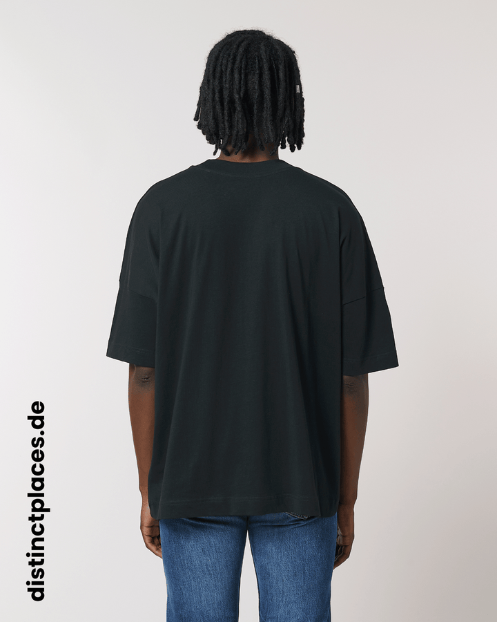 Mann von hinten trägt schwarzes fairtrade, vegan und bio-baumwoll Oversized T-Shirt mit einem minimalistischem weißen Logo, beziehungsweise Wappen für Ludwigshafen