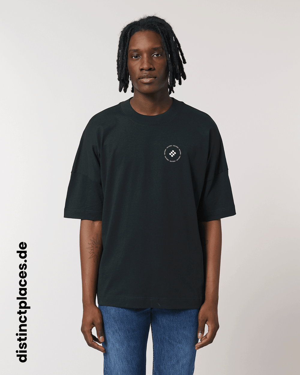 Mann von vorne trägt schwarzes fairtrade, vegan und bio-baumwoll T-Shirt mit einem minimalistischem weißen Logo, beziehungsweise Wappen und Schriftzug für Bayern