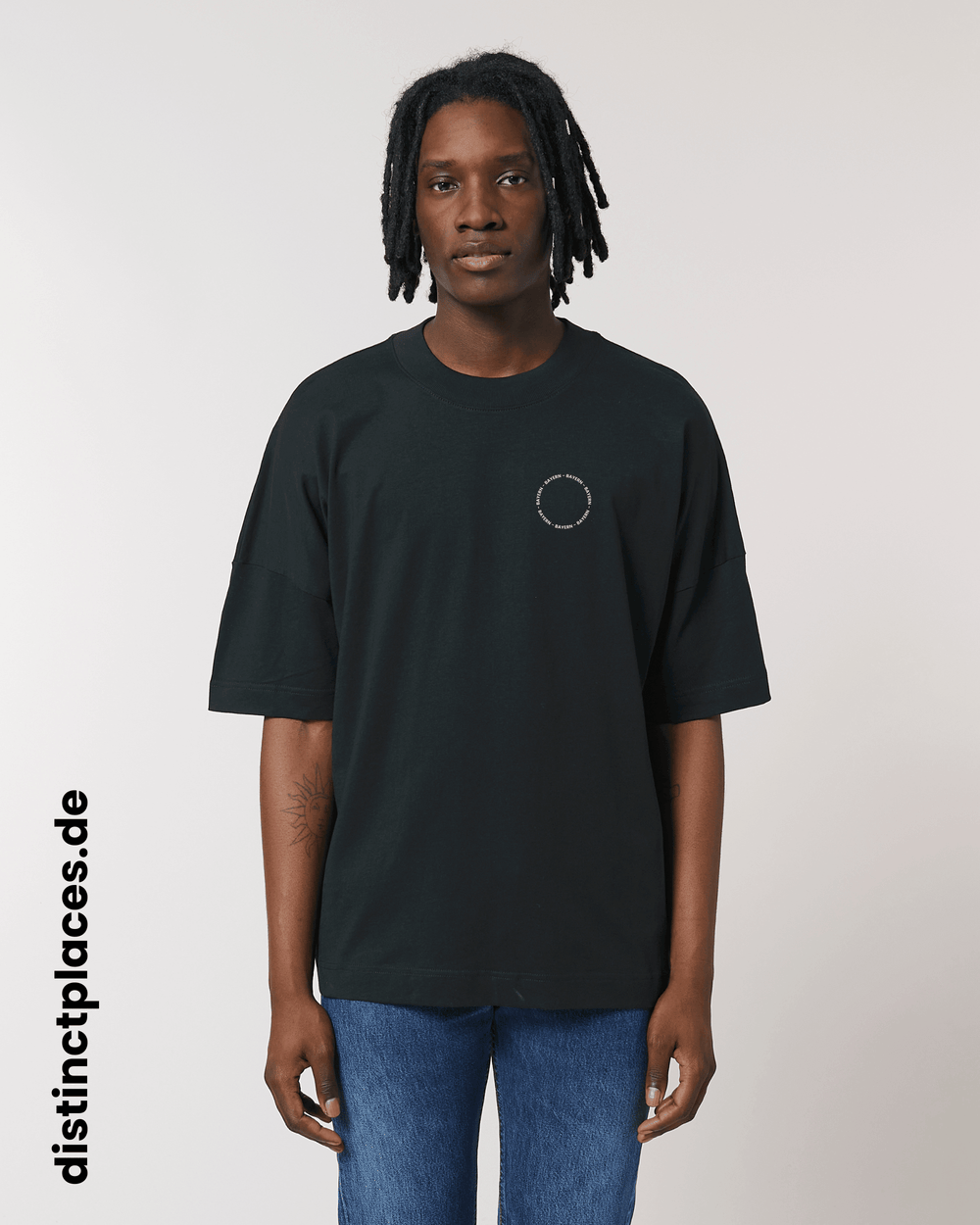 Mann von vorne trägt schwarzes fairtrade, vegan und bio-baumwoll T-Shirt mit einem minimalistischem weißen Logo, beziehungsweise Schriftzug für Bayern