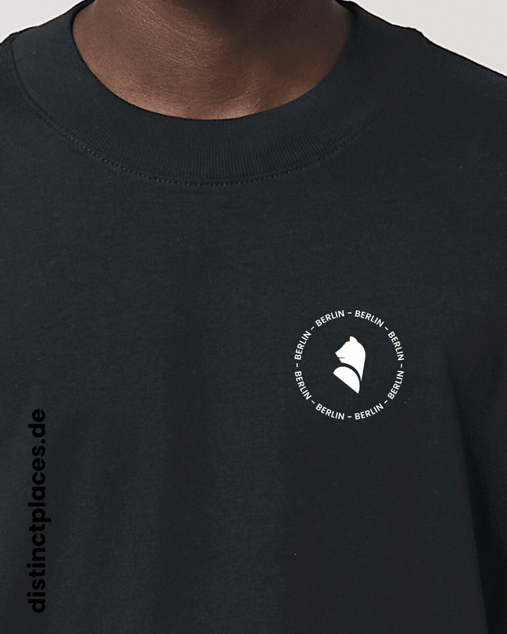 Detailansicht schwarzes fairtrade, vegan und bio-baumwoll Oversized T-Shirt von vorne mit einem minimalistischem weißen Logo, beziehungsweise Wappen und Schriftzug für Berlin