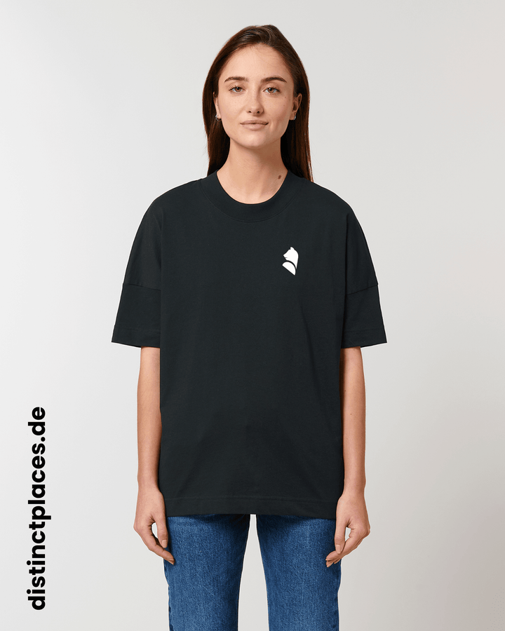 Frau von vorne trägt schwarzes fairtrade, vegan und bio-baumwoll T-Shirt mit einem minimalistischem weißen Logo, beziehungsweise Wappen für Berlin