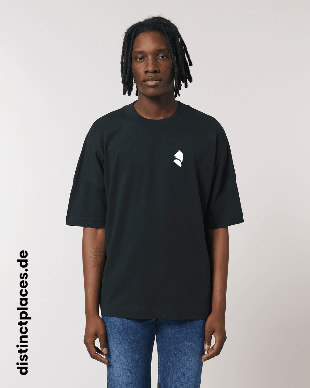 Mann von vorne trägt schwarzes fairtrade, vegan und bio-baumwoll T-Shirt mit einem minimalistischem weißen Logo, beziehungsweise Wappen für Berlin