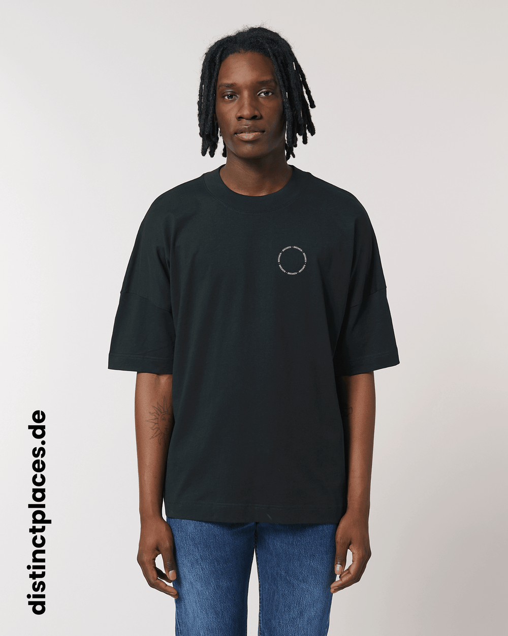 Mann von vorne trägt schwarzes fairtrade, vegan und bio-baumwoll T-Shirt mit einem minimalistischem weißen Logo, beziehungsweise Schriftzug für Bremen