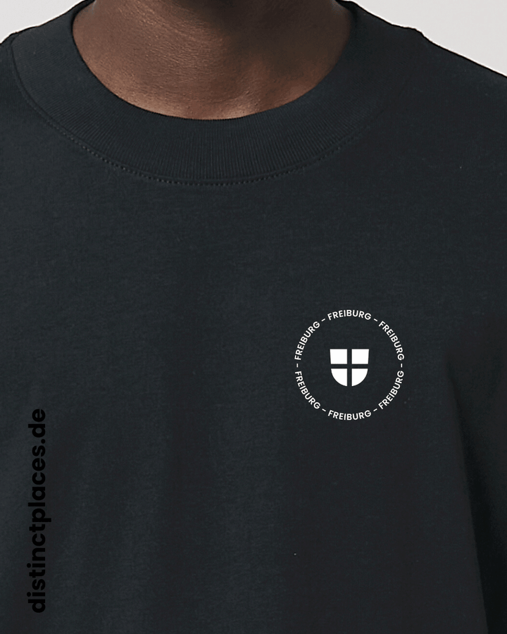 Detailansicht schwarzes fairtrade, vegan und bio-baumwoll Oversized T-Shirt von vorne mit einem minimalistischem weißen Logo, beziehungsweise Wappen und Schriftzug für Freiburg