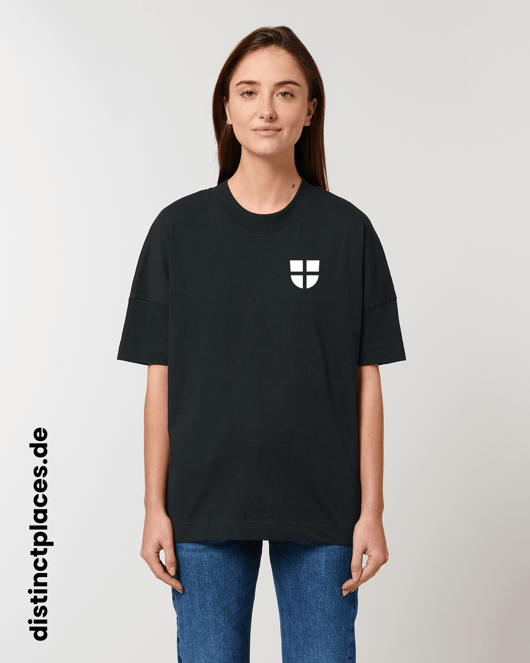 Frau von vorne trägt schwarzes fairtrade, vegan und bio-baumwoll T-Shirt mit einem minimalistischem weißen Logo, beziehungsweise Wappen für Freiburg