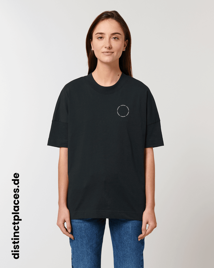 Frau von vorne trägt schwarzes fairtrade, vegan und bio-baumwoll T-Shirt mit einem minimalistischem weißen Logo, beziehungsweise Schriftzug für Hamburg