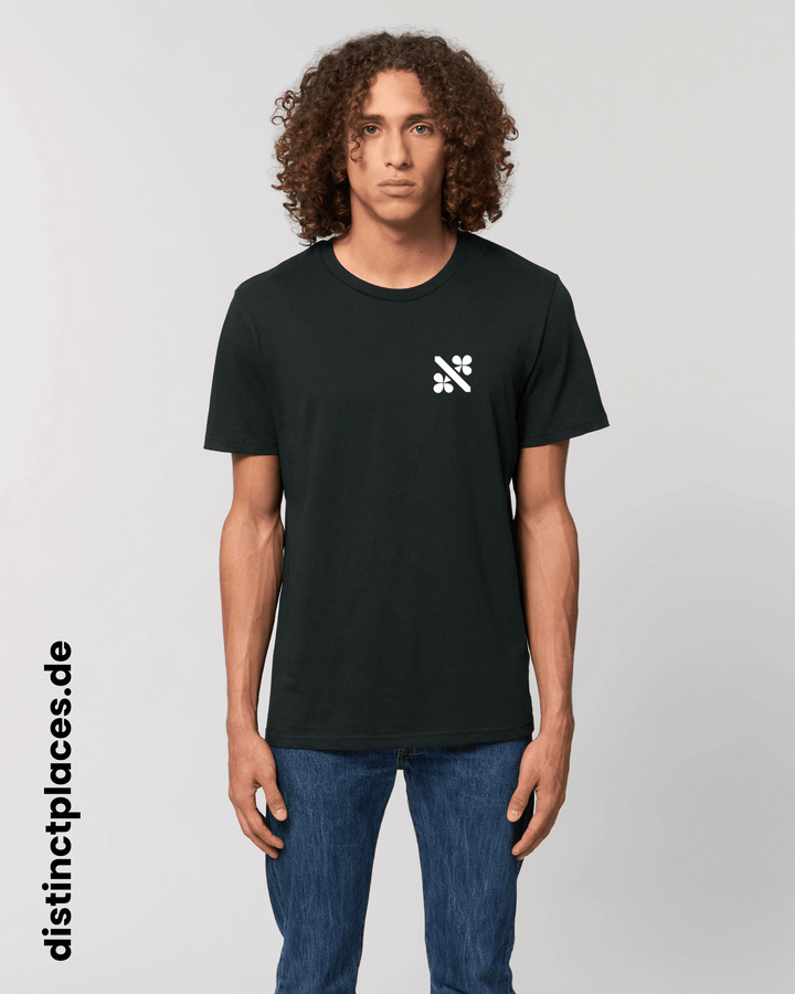 Mann von vorne trägt schwarzes fairtrade, vegan und bio-baumwoll T-Shirt mit einem minimalistischem weißen Logo, beziehungsweise Wappen für Kassel