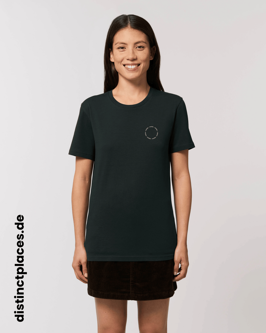 Frau von vorne trägt schwarzes fairtrade, vegan und bio-baumwoll T-Shirt mit einem minimalistischem weißen Logo, beziehungsweise Schriftzug für Kassel