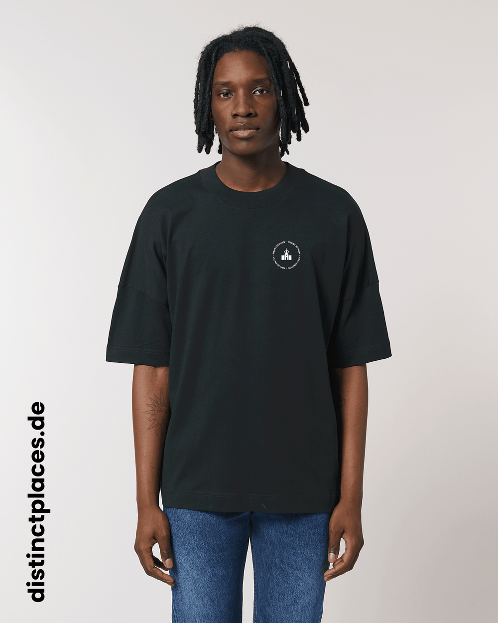 Mann von vorne trägt schwarzes fairtrade, vegan und bio-baumwoll T-Shirt mit einem minimalistischem weißen Logo, beziehungsweise Wappen und Schriftzug für Neunkirchen