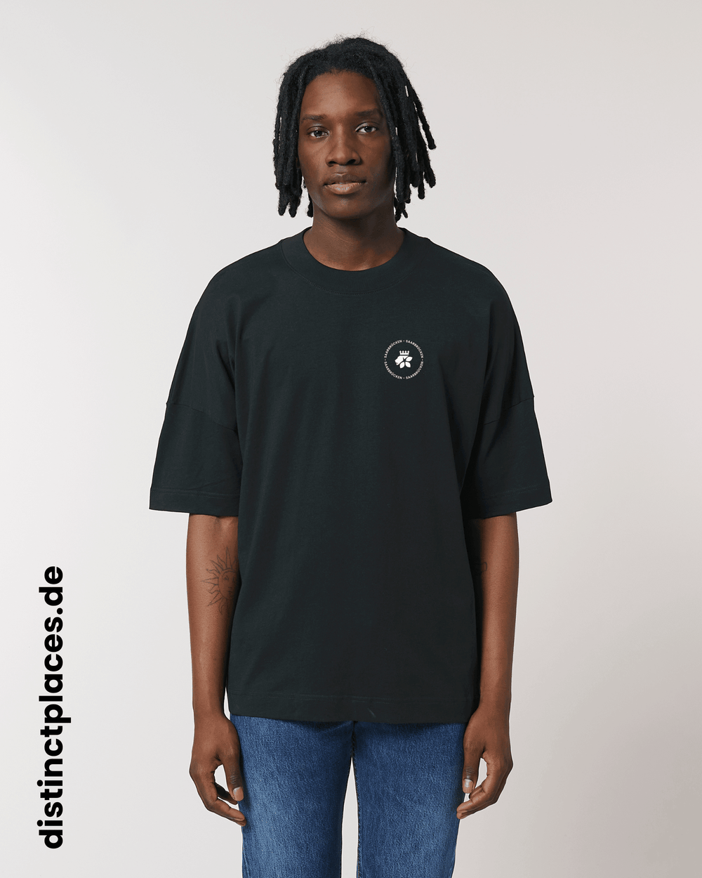 Mann von vorne trägt schwarzes fairtrade, vegan und bio-baumwoll T-Shirt mit einem minimalistischem weißen Logo, beziehungsweise Wappen und Schriftzug für Saarbrücken
