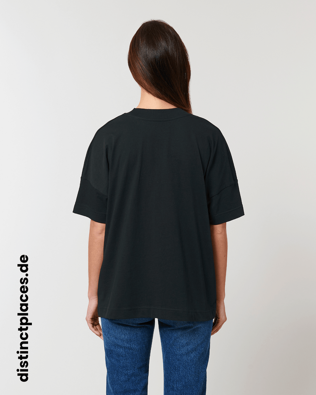 Frau von hinten trägt schwarzes fairtrade, vegan und bio-baumwoll Oversized T-Shirt mit einem minimalistischem weißen Logo, beziehungsweise Schriftzug für Saarbrücken