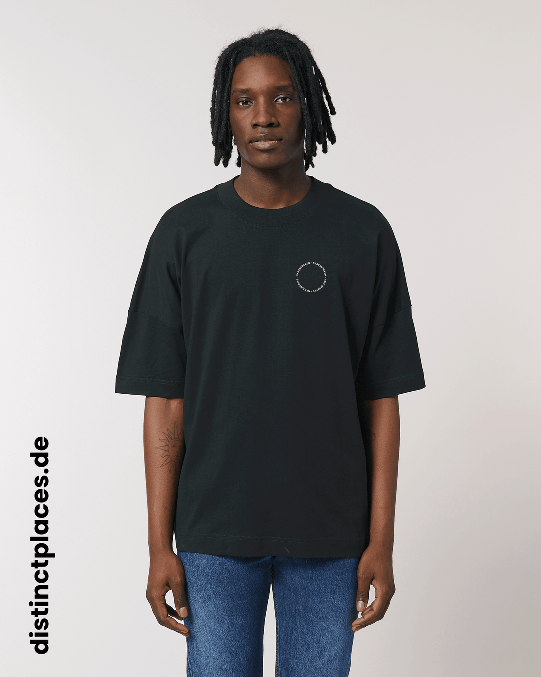 Mann von vorne trägt schwarzes fairtrade, vegan und bio-baumwoll T-Shirt mit einem minimalistischem weißen Logo, beziehungsweise Schriftzug für Saarbrücken
